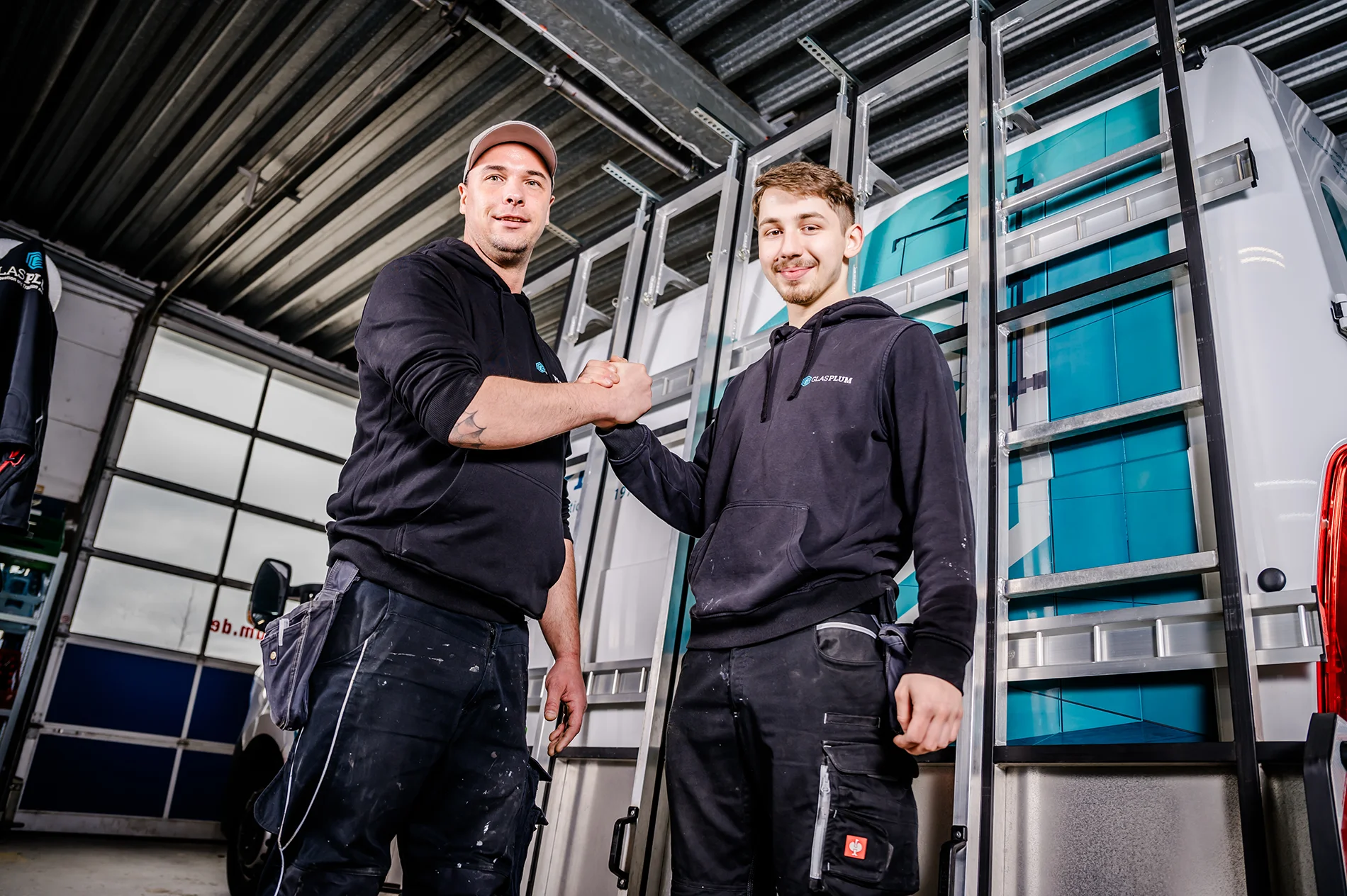 Zwei Junge Glaser Jülich von Glas Plum machen einen Handschlag.